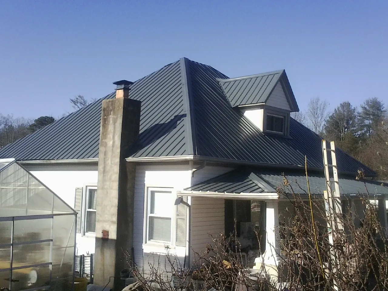 Dark blue standing seam metal roof on a white farmhouse with dormer — Slate & Tile Roof Repair by Roofing Brothers in Lomita