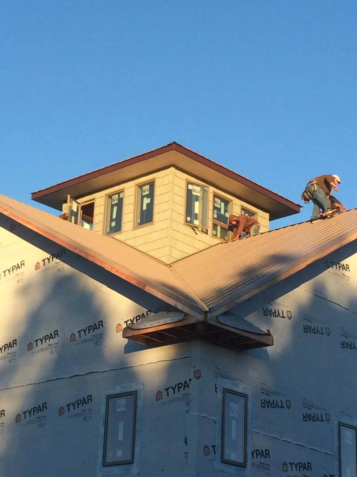 Roofers working around a rooftop cupola on a new metal roof at sunset — Roof Waterproofing in Lomita by Roofing Brothers